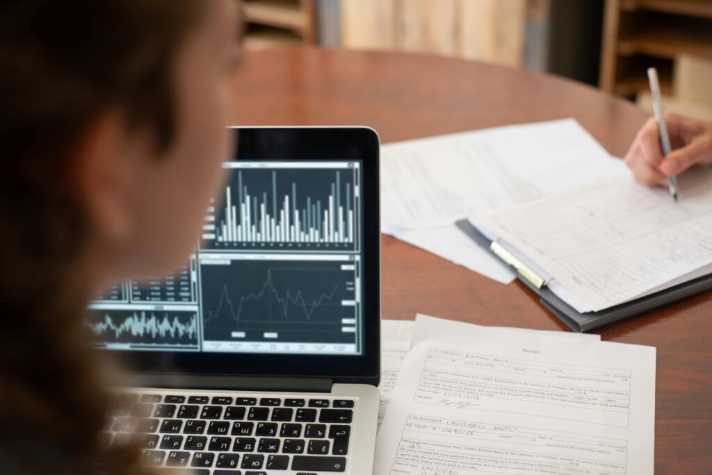 A professional analyzing financial charts on a laptop with investment documents on the table, representing data-driven decisions in peer-to-peer lending and CFA careers.